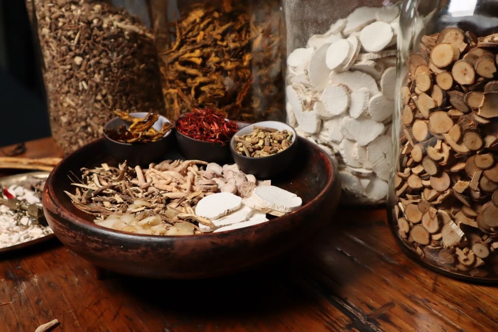 Traditional Chinese medicine herbs arranged in bowls and glass jars